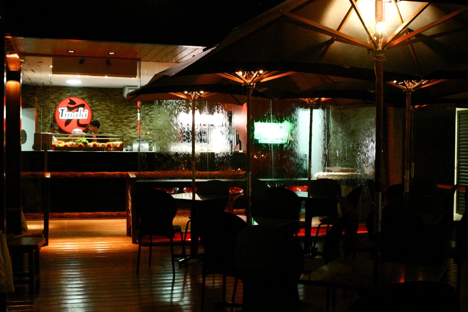 Deck à noite com o logo Tmaki iluminado e o balcão de sushi