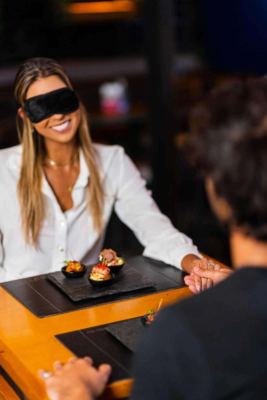 Convidada vendada sorri à mesa