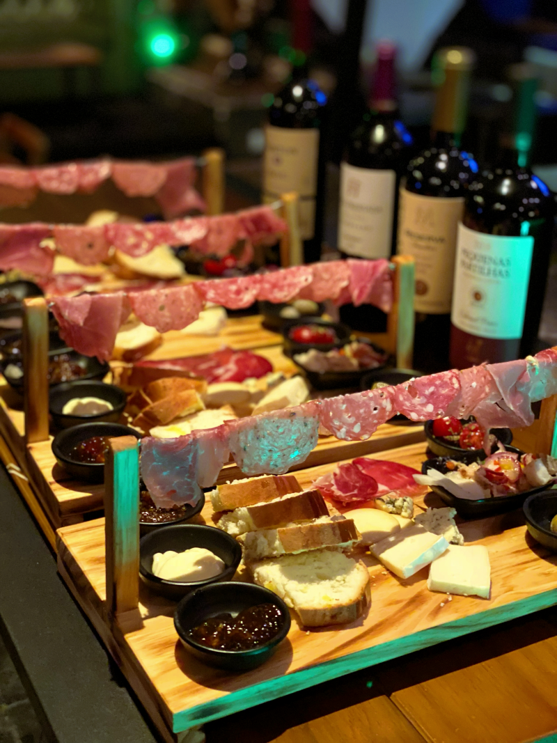 Varais de frios, queijos e pães com vinhos sul-americanos